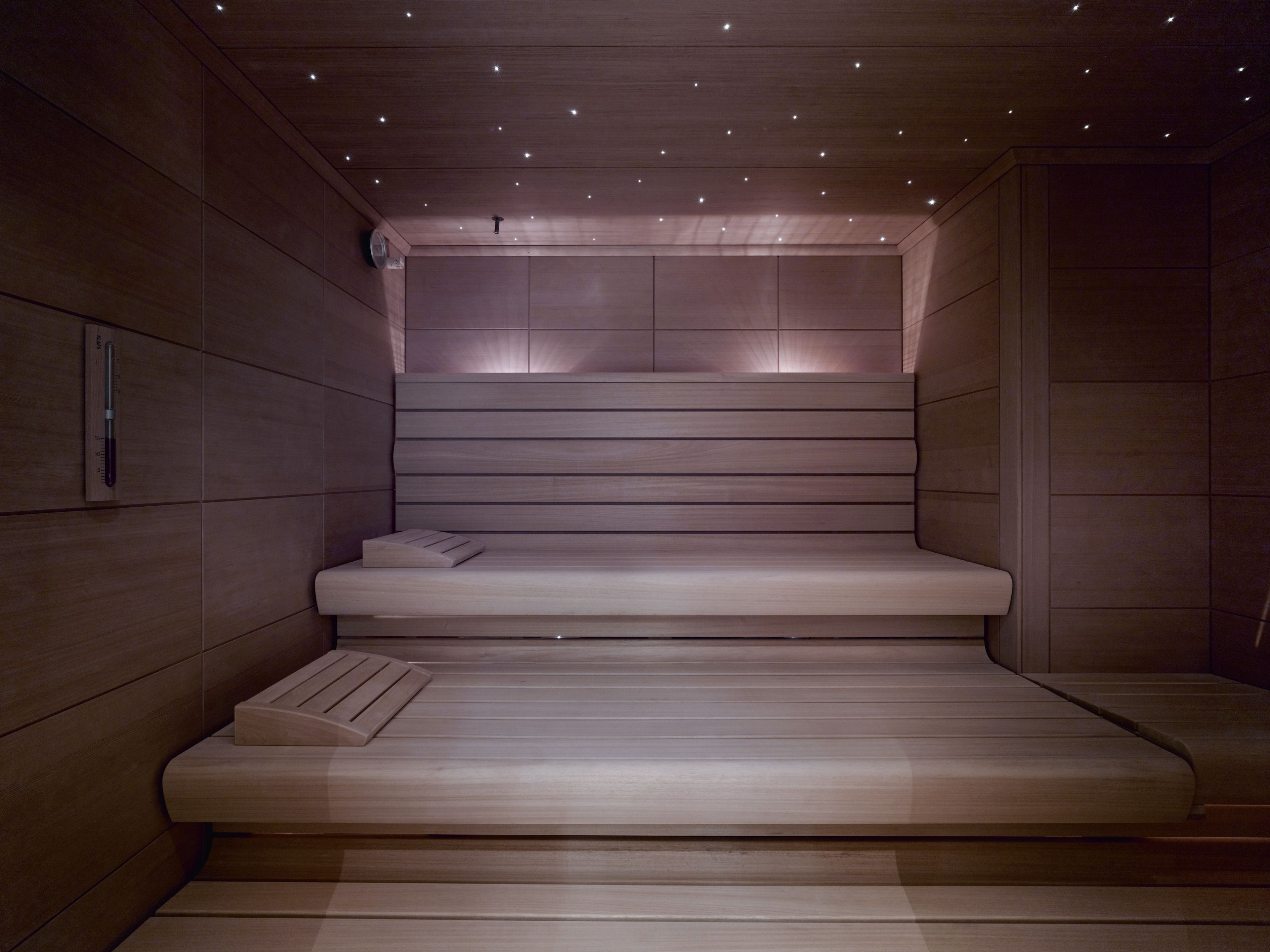 Una sauna moderna con bancos de madera y techo inclinado con iluminación empotrada.