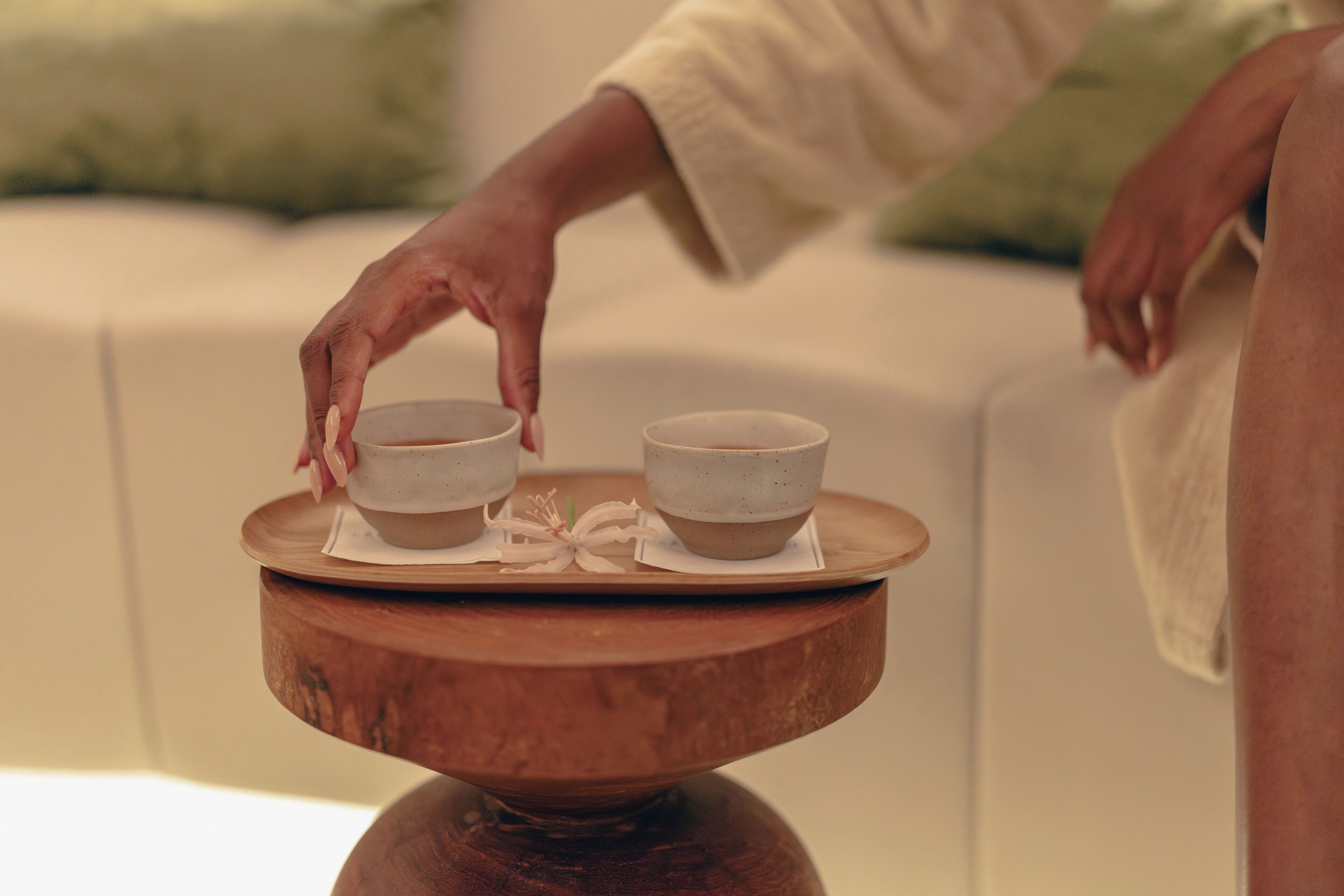 A wooden tray with two ceramic cups on a table.