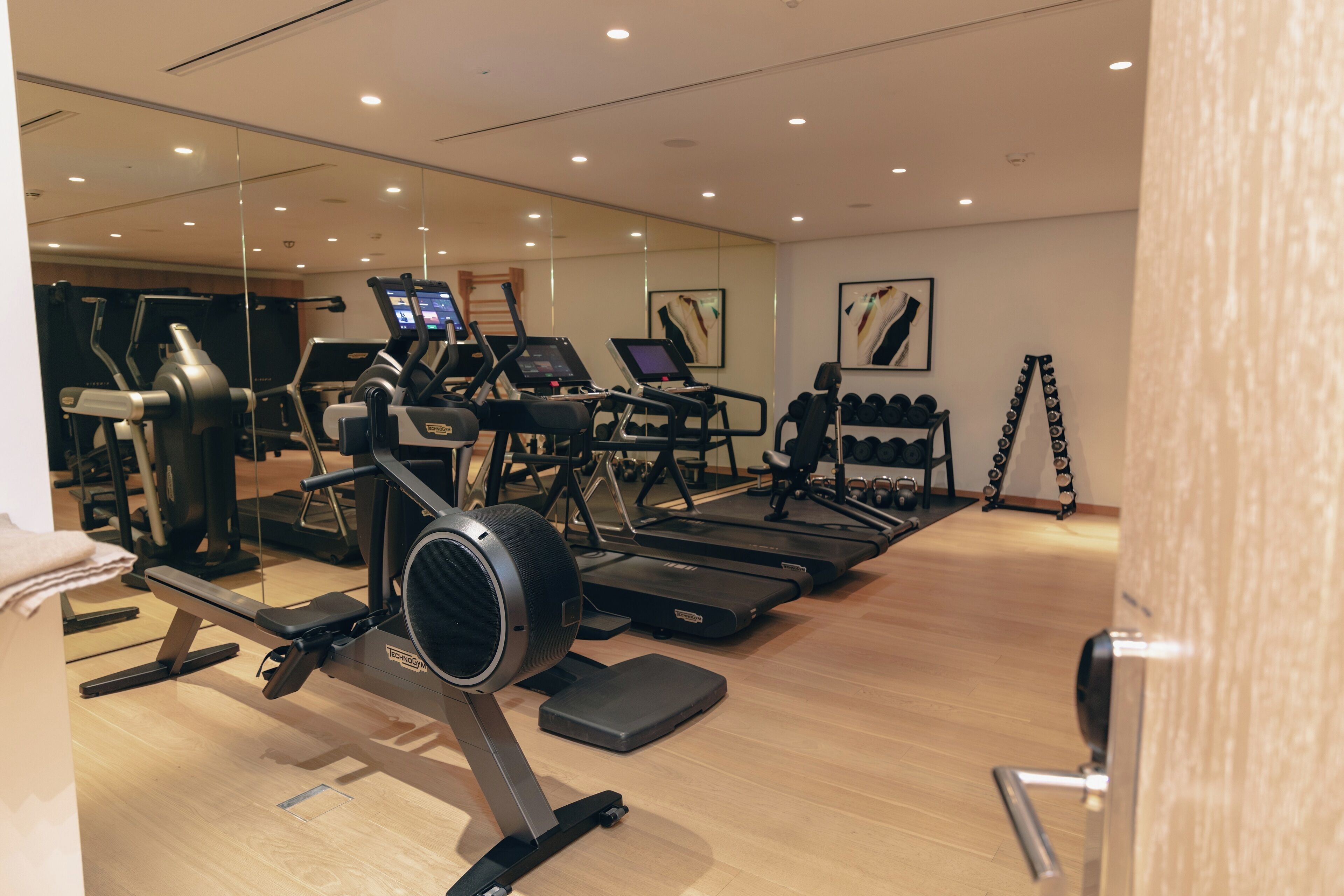 Un gimnasio con cintas de correr, elípticas y pesas sueltas.