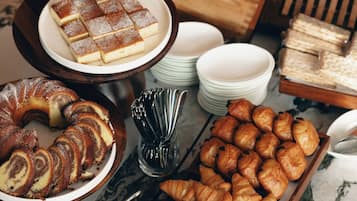 Un buffet proposant une variété de produits de boulangerie, notamment des pâtisseries, du pain et des desserts.