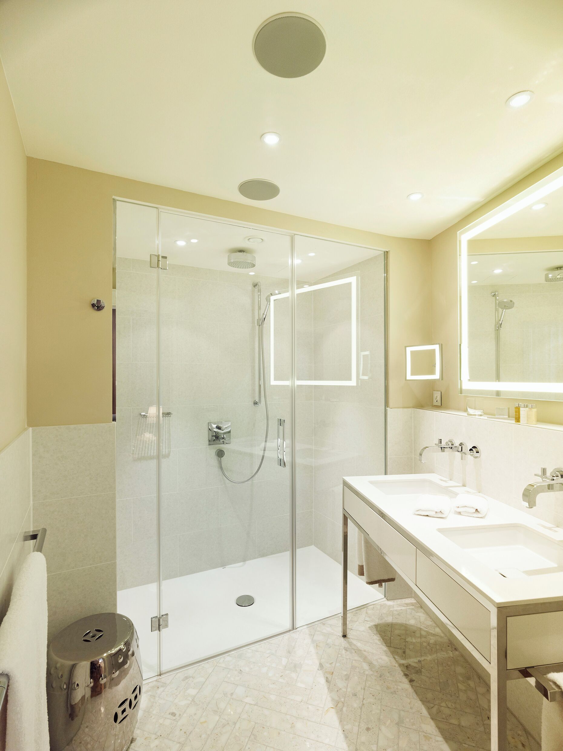 A modern bathroom with a glass-enclosed shower, a double sink vanity, and a large mirror above the sink.