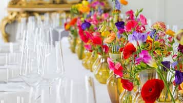 A table set with clear glasses and colorful flower arrangements in yellow vases.