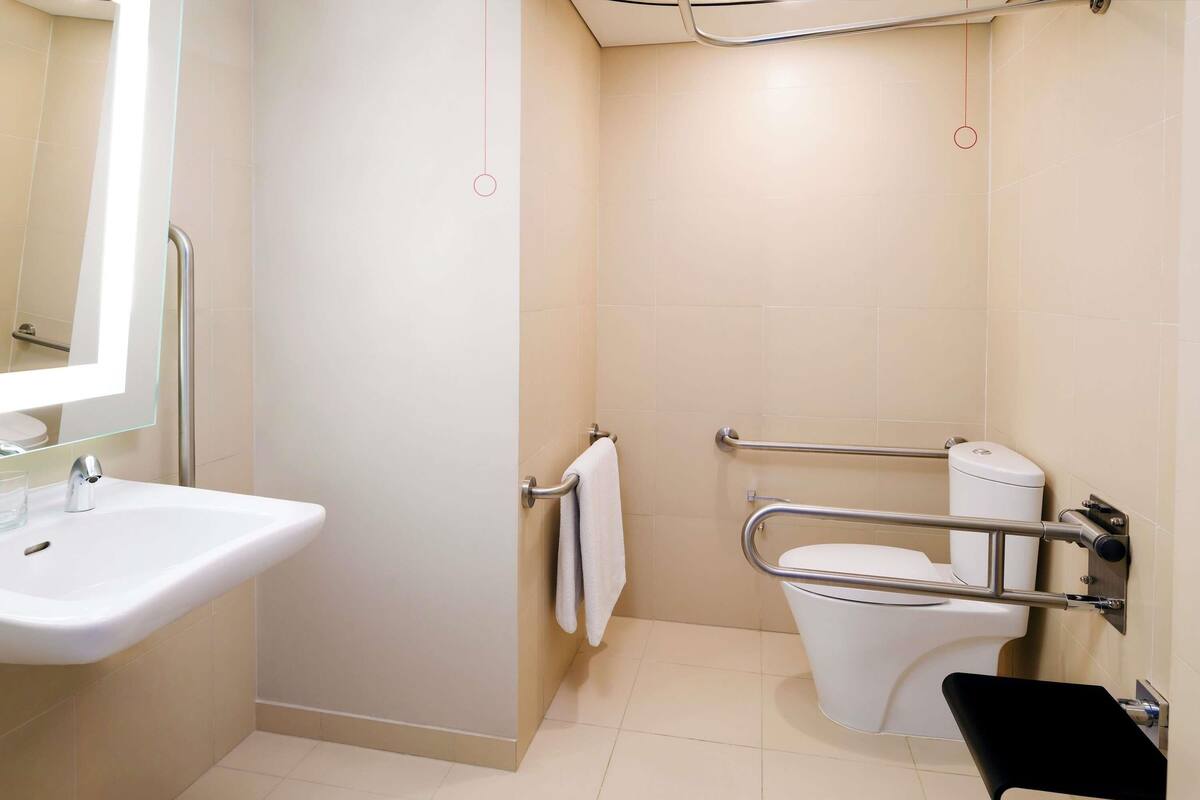 A bathroom with a sink, toilet, and grab bars.