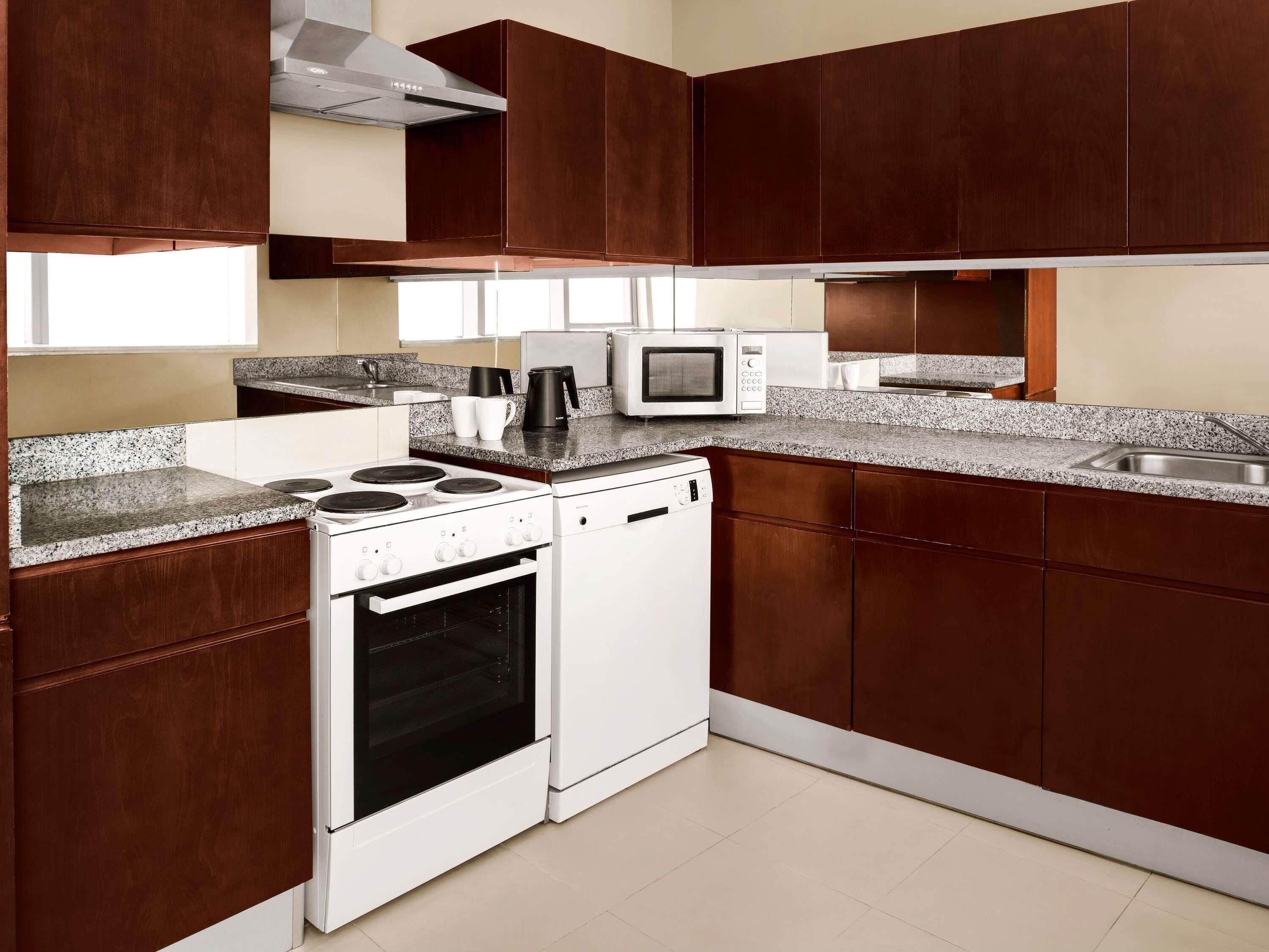 A kitchen with dark wooden cabinets, a white stove, a microwave, and a dishwasher.