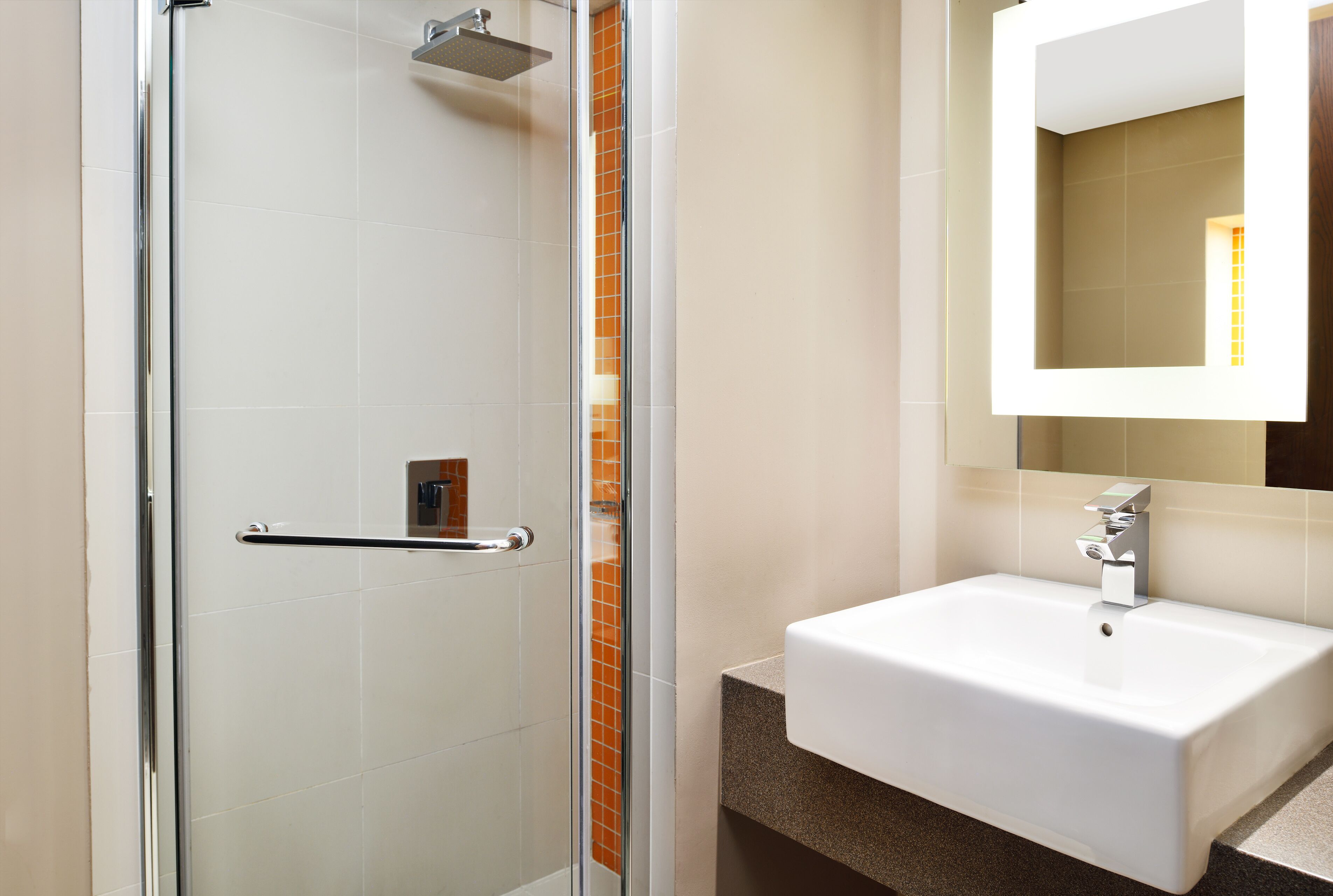 A modern bathroom with a glass shower enclosure, a white sink, and a mirror above it.