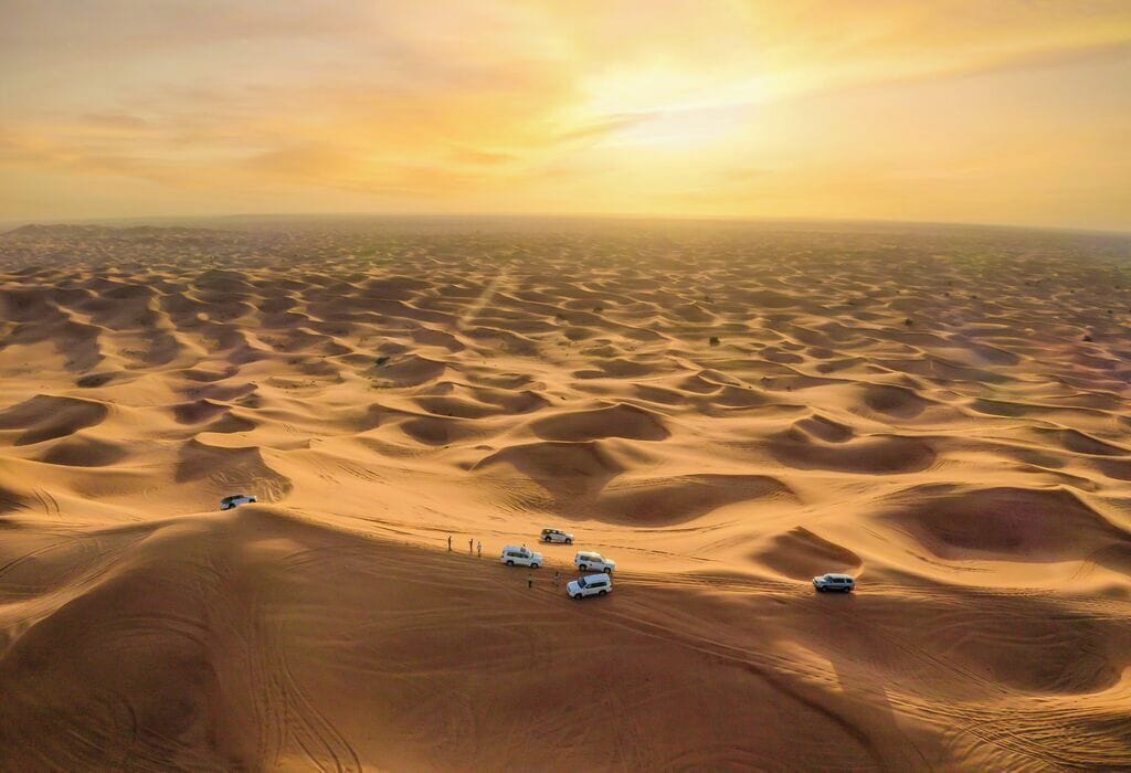 A desert landscape with sand dunes and vehicles.