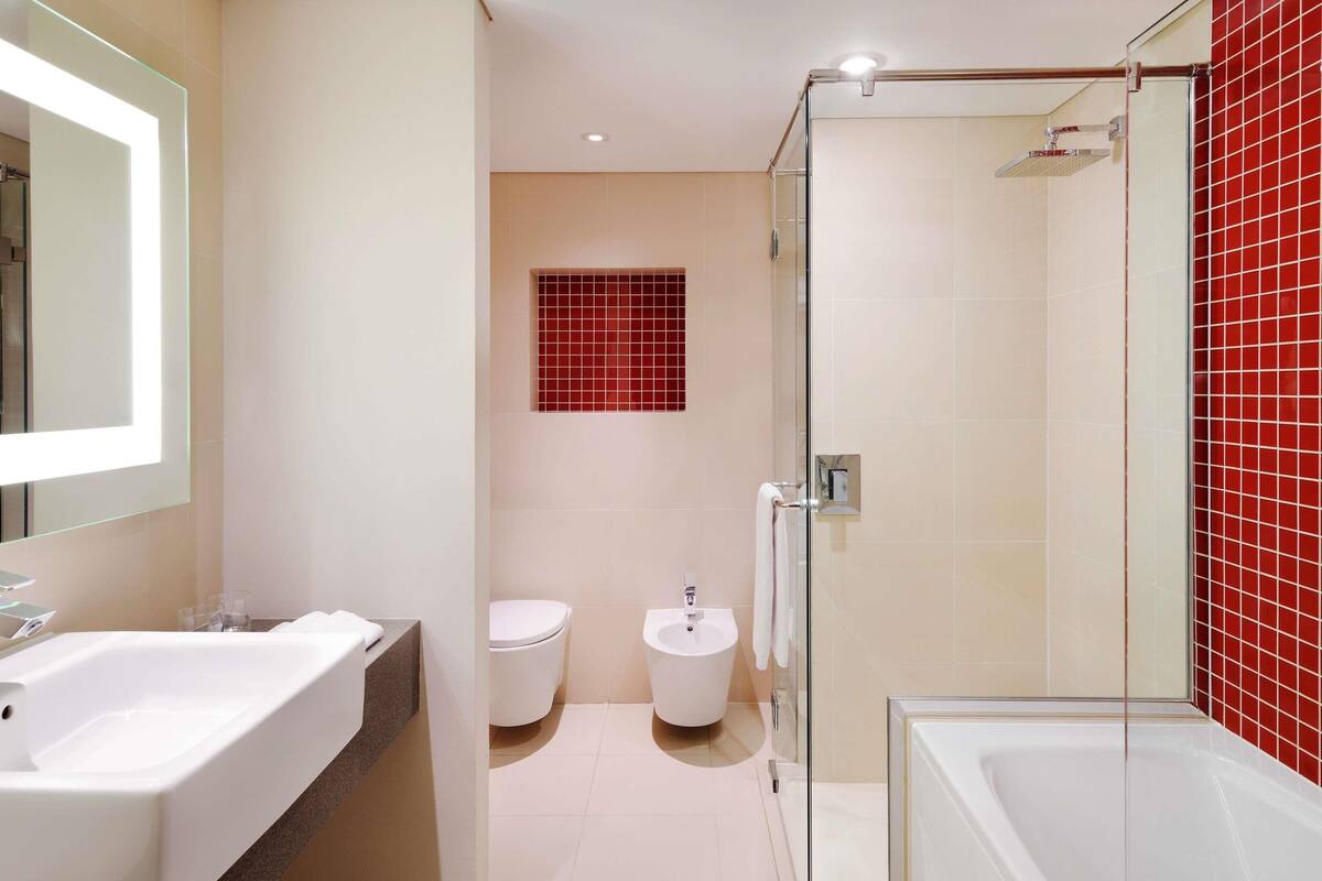 A modern bathroom with a glass-enclosed shower, a white sink, and a toilet.