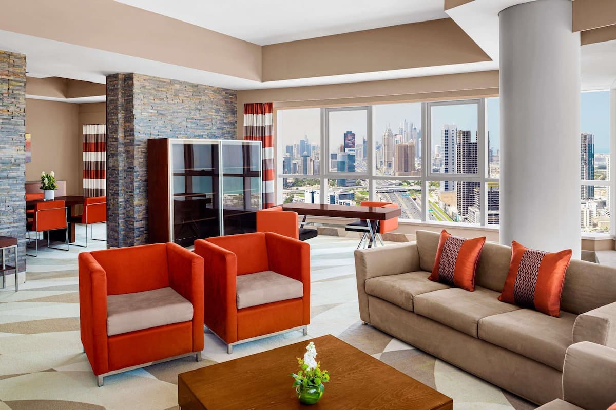 Un salon moderne avec vue sur la ville, comprenant un canapé, des fauteuils, une table basse et une cheminée.