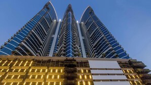 Un edificio de gran altura con un diseño arquitectónico moderno, que cuenta con varios balcones y un fachada de vidrio reflectante.