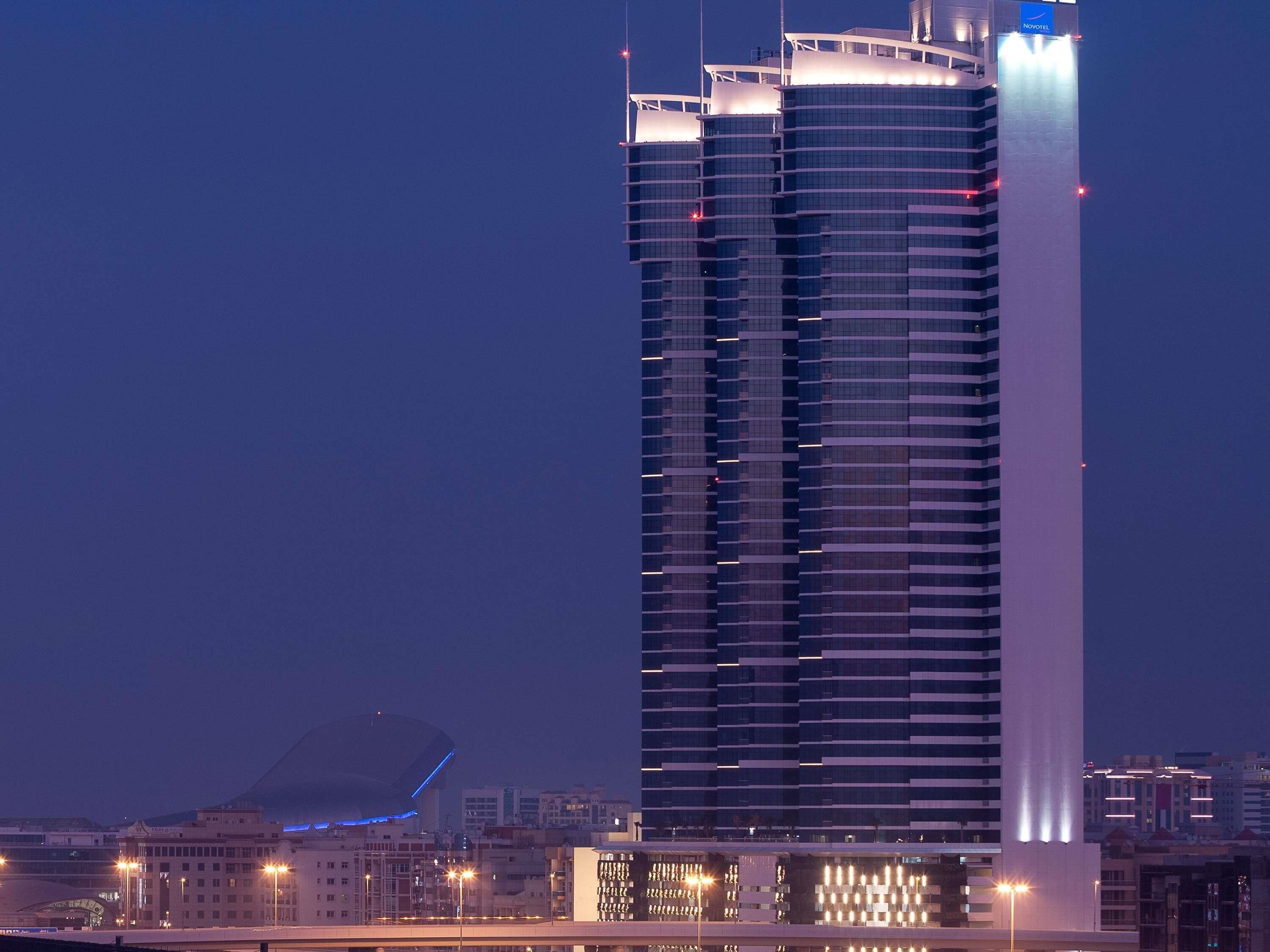 Un hôtel de grande hauteur au design moderne, comprenant de nombreux étages et une bande lumineuse verticale bien visible.