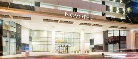 A hotel entrance with a modern design, glass facade, and the name 'NOVOTEL' prominently displayed.