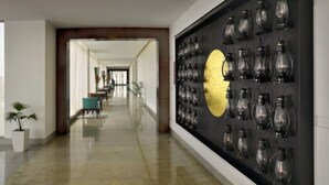 A hallway with a wall-mounted display of glassware and a large yellow circular object. - Four Points by Sheraton New Delhi, Airport Highway (New Delhi)
