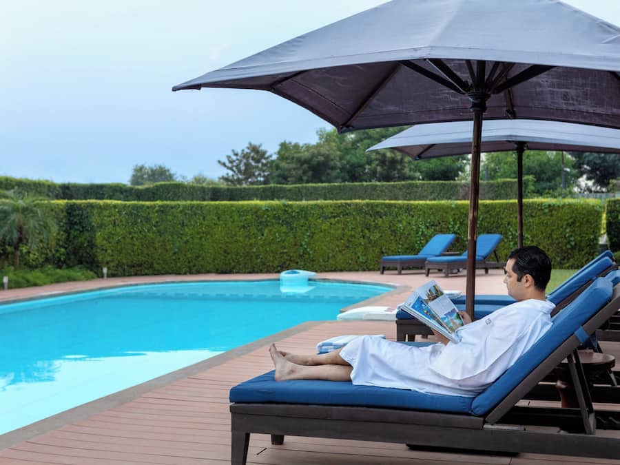 Una piscina al aire libre, sombrillas, sillones reclinables de piscina