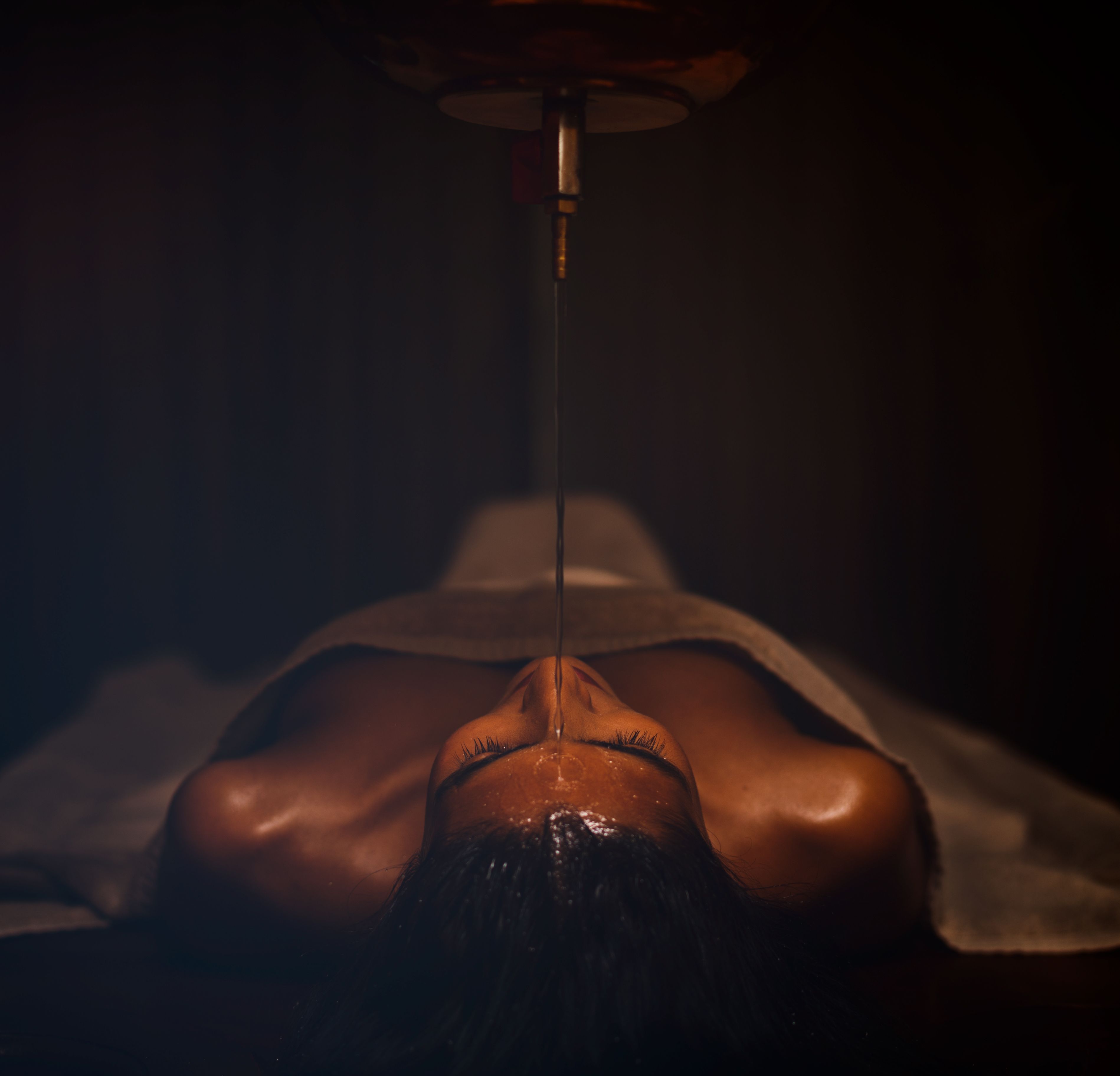 A person lying face down on a massage table with a treatment being applied to their back.