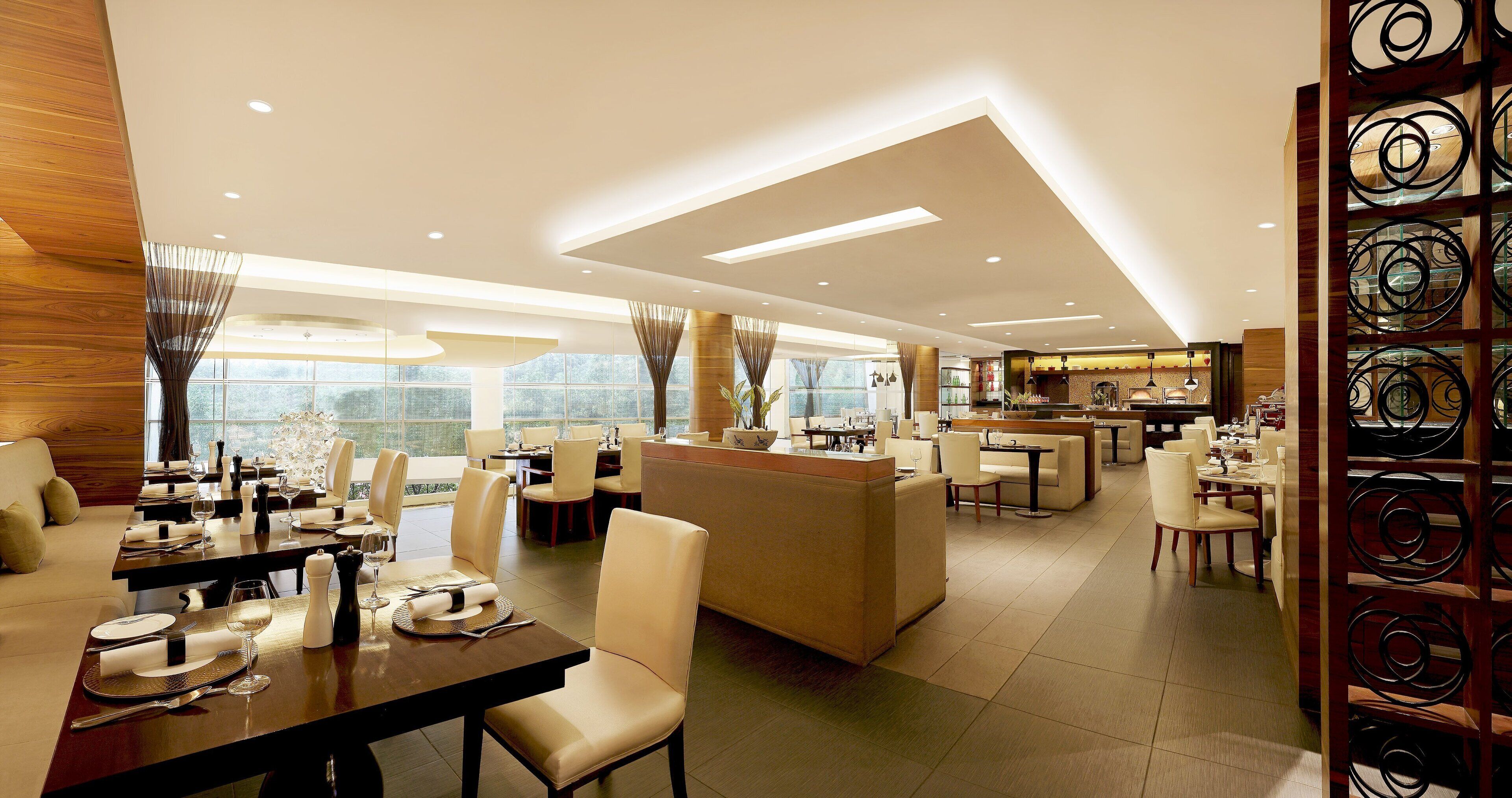 A modern hotel dining area with multiple seating options, a bar, and a view of the outdoors.