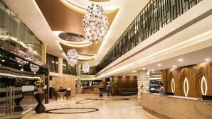 A spacious lobby with a marble floor, a reception desk, and a modern chandelier. - Crowne Plaza Ahmedabad City Centre by IHG (Ahmedabad)