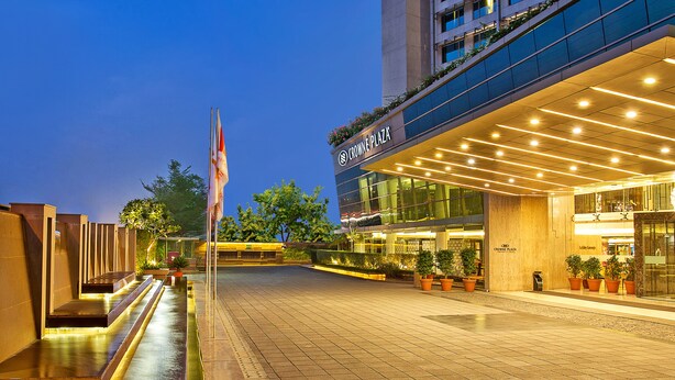 A modern hotel entrance with a well-lit facade, outdoor seating area, and potted plants. - Crowne Plaza Ahmedabad City Centre by IHG (Ahmedabad)