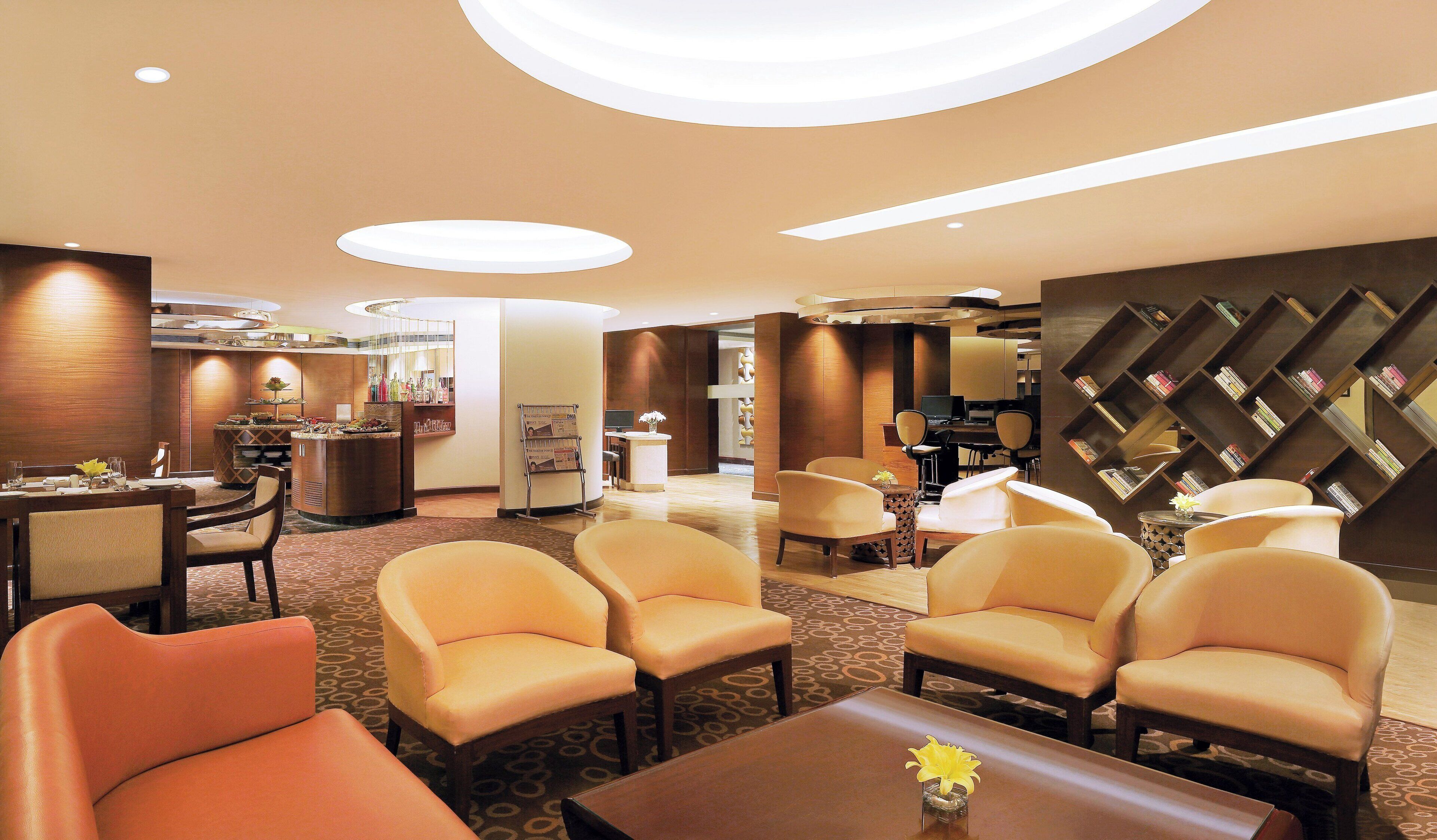 Un hall de hotel con mostrador de recepción, zona de estar y una pared con estantería.
