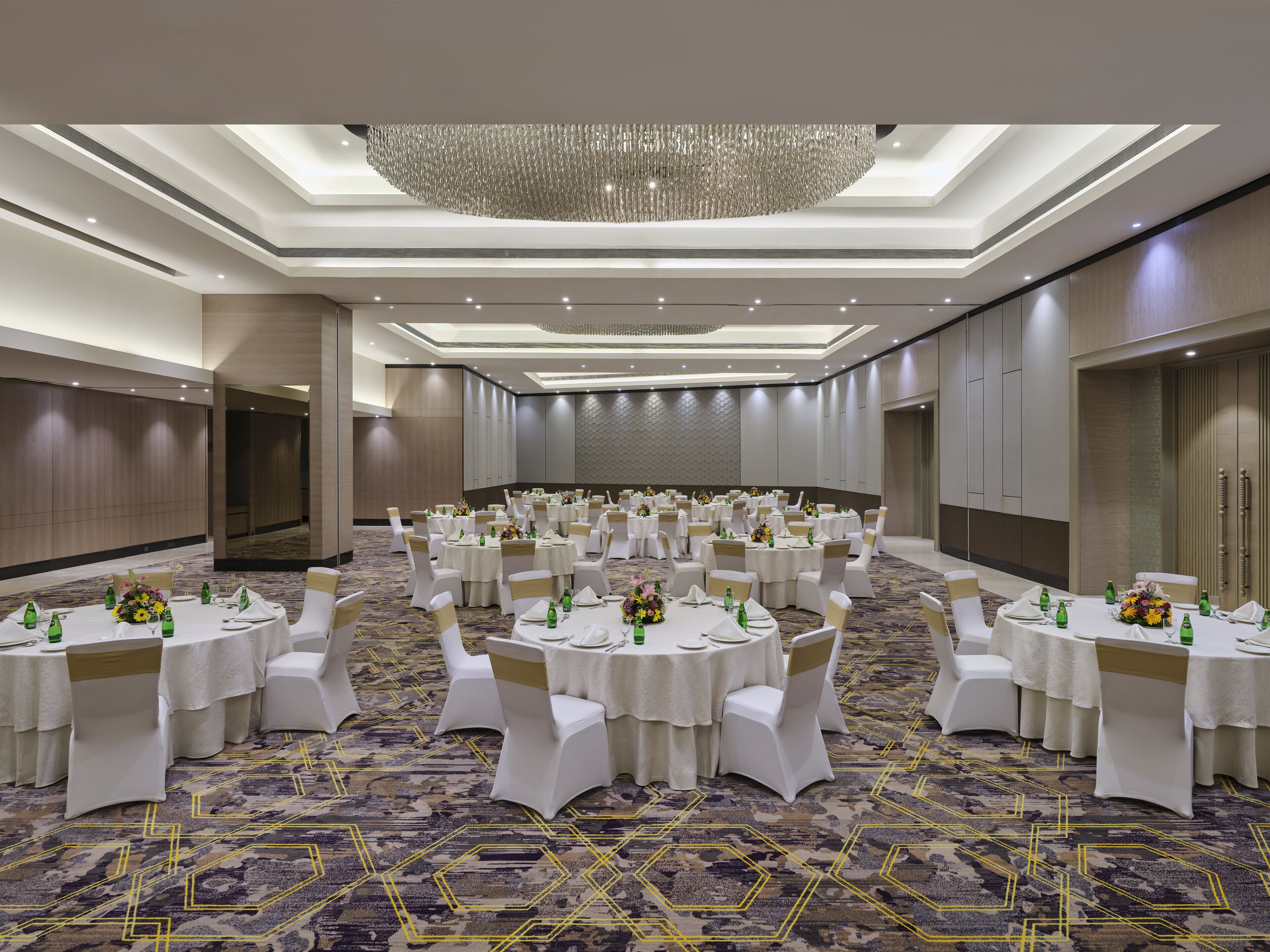 A large banquet hall with round tables, white tablecloths, and gold sashes.