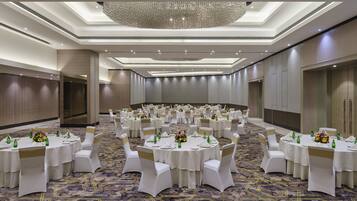 A large banquet hall with round tables, white tablecloths, and gold sashes.
