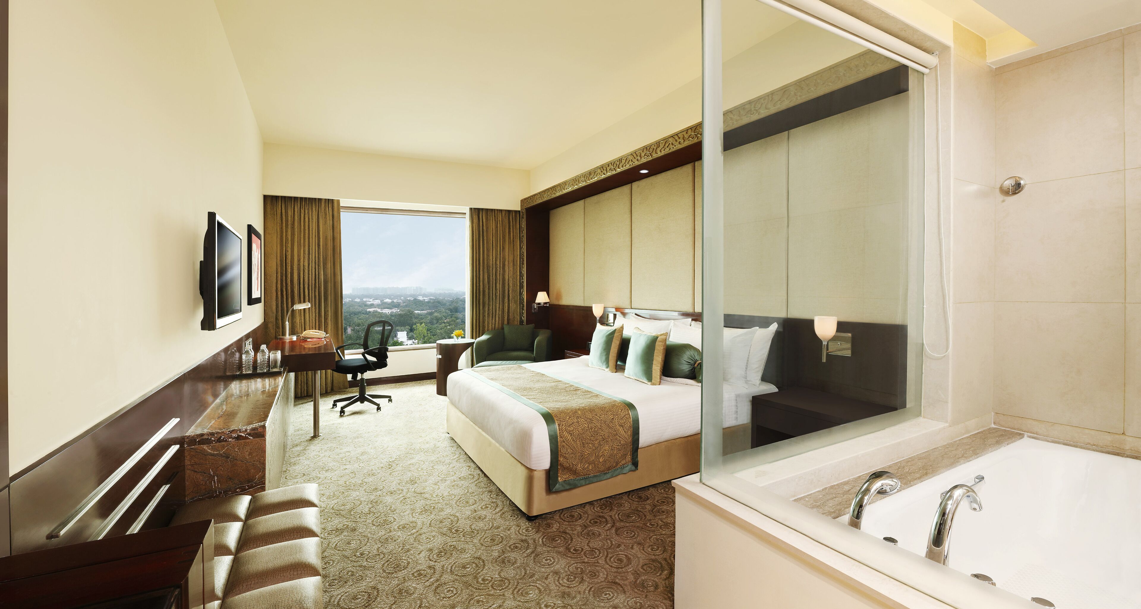 A hotel room with a large bed, a desk, a chair, a TV, and a bathroom with a bathtub and shower.