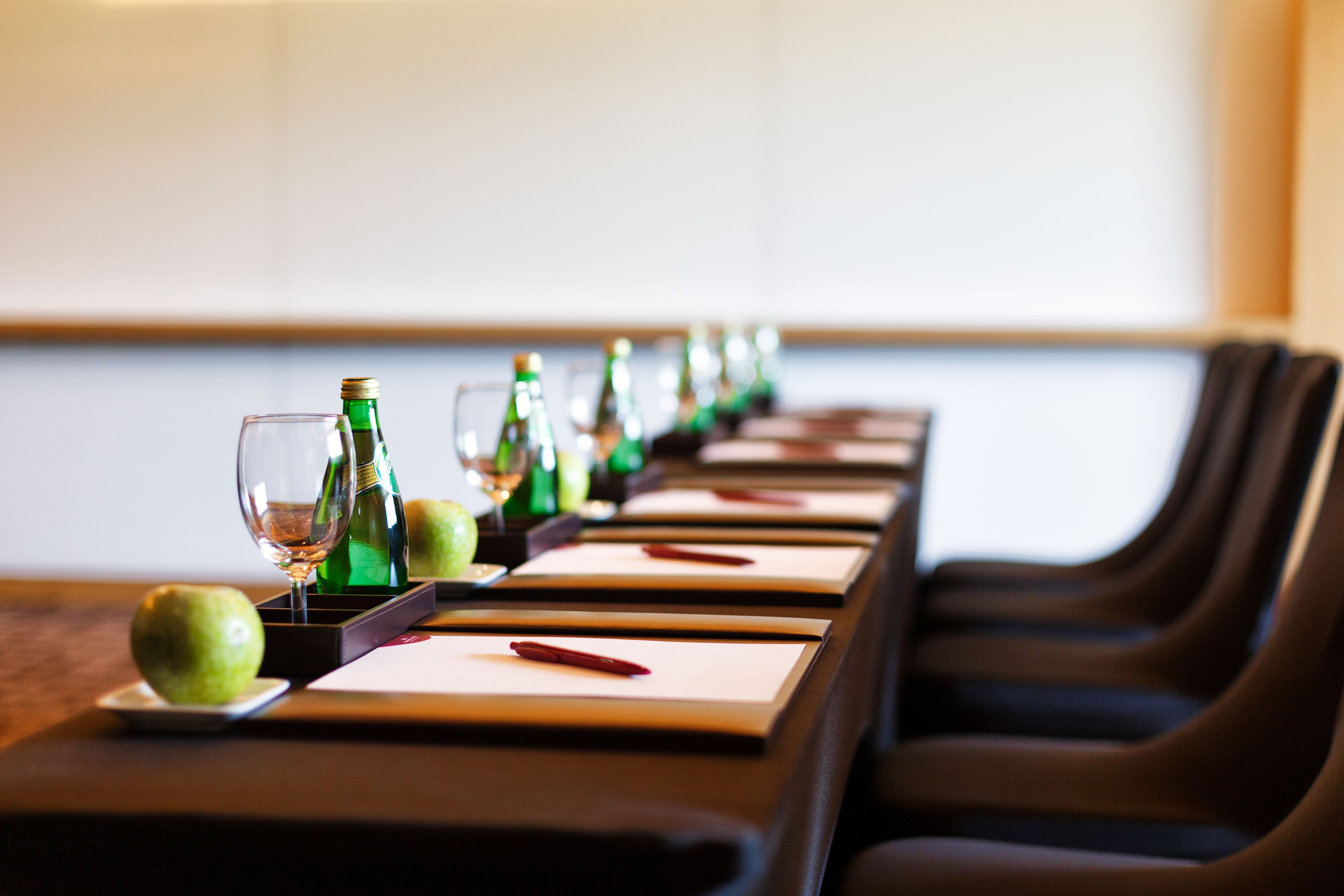 A conference table with chairs, green bottles, and glasses.