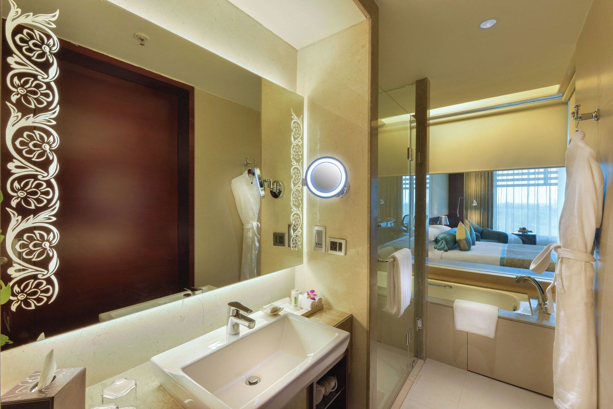 A modern bathroom with a large mirror, a sink, a glass shower enclosure, and a robe hanging on the wall.