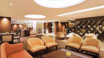 Un hall de hotel con mostrador de recepción, zona de estar y una pared con estanterías.