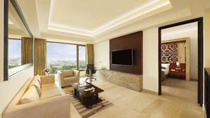 A modern living room with a sofa, coffee table, and a TV mounted on the wall. - Crowne Plaza Ahmedabad City Centre by IHG (Ahmedabad)