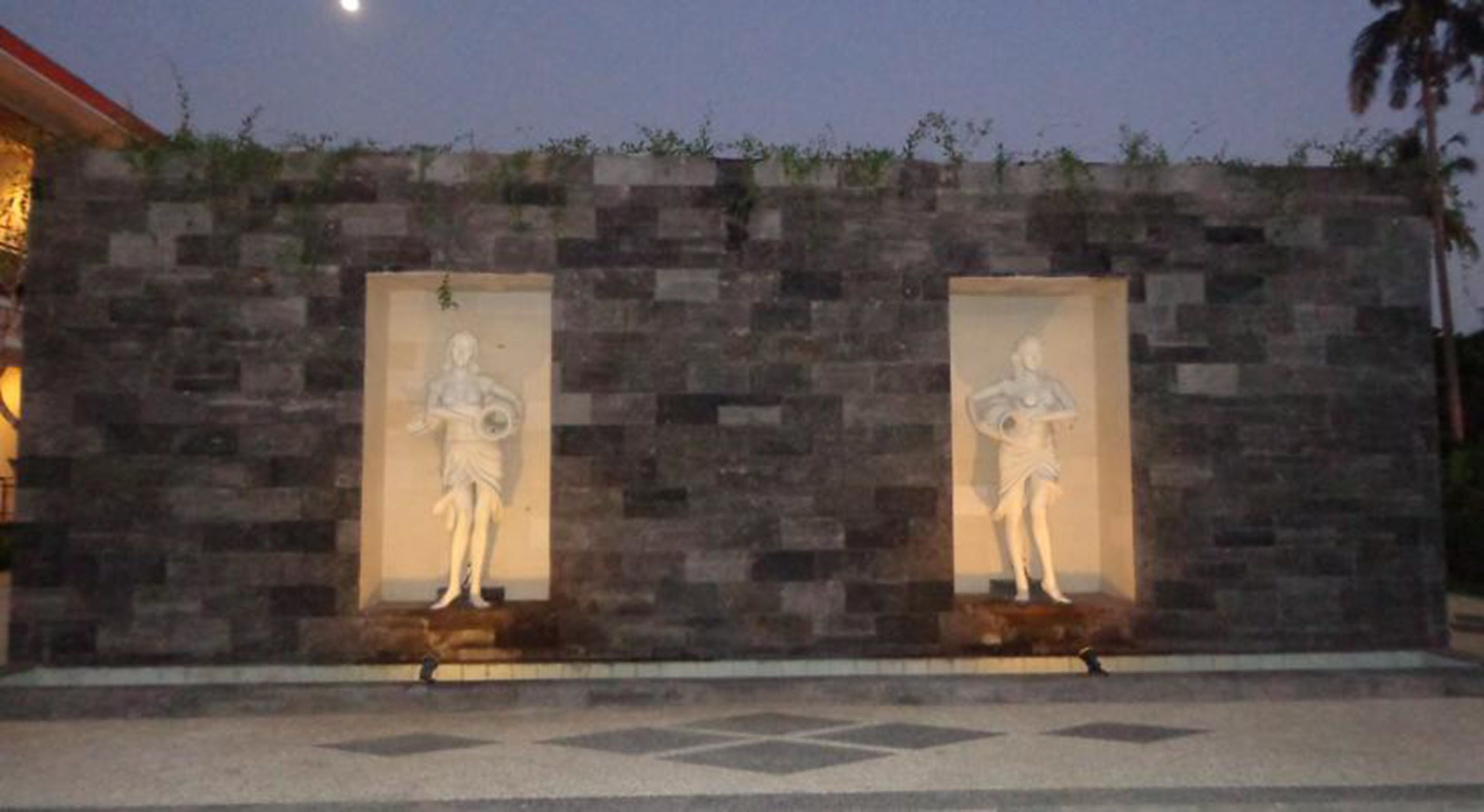 A stone wall with two niches containing statues.