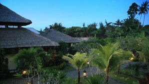 A resort with thatched-roof buildings, lush greenery, and outdoor lighting.