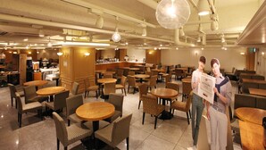 A hotel lobby with multiple seating areas, a reception desk, and a bar.