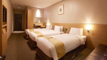 A hotel room with two beds, a wooden headboard, a nightstand, a mirror, and a framed picture on the wall.