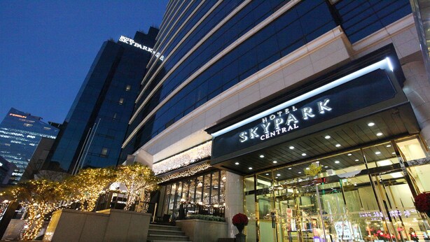 A hotel named 'SKY PARK CENTRAL' with a modern facade, large windows, and a visible entrance.