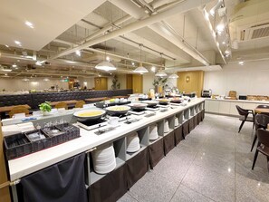 Un buffet avec plusieurs points de service, un espace détente avec un canapé et un intérieur propre et bien éclairé.