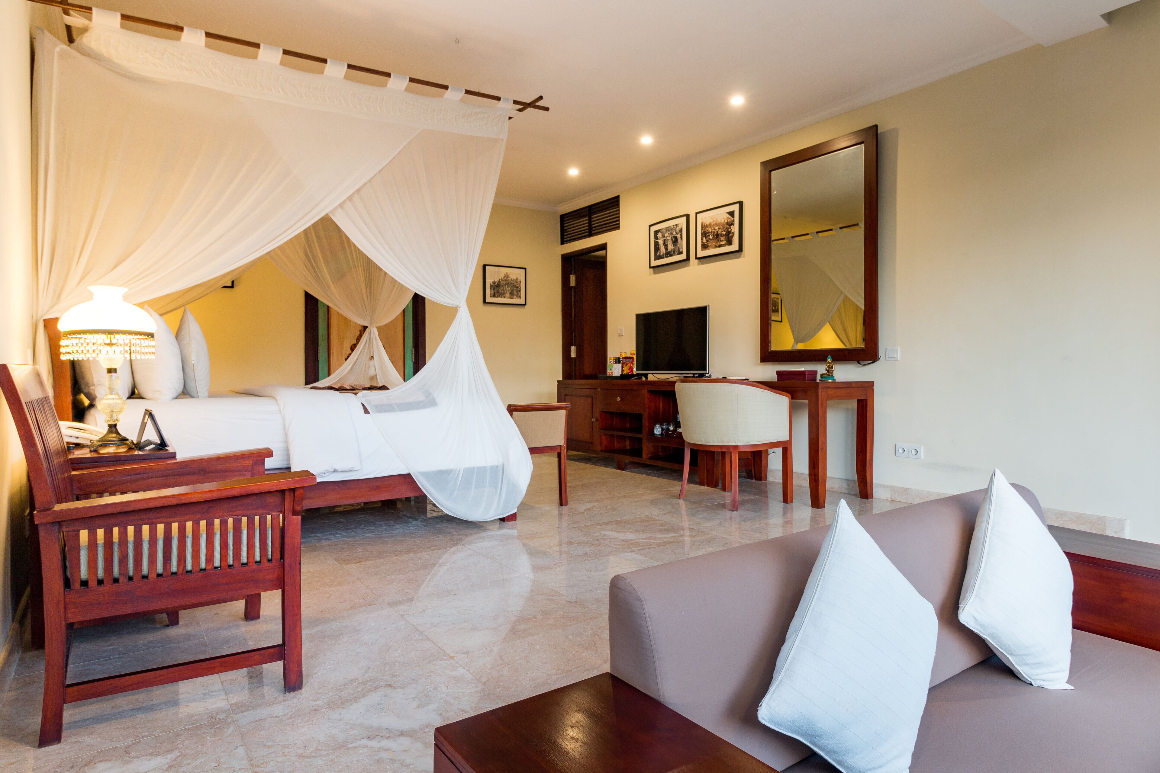 A hotel room with a bed, a desk, a chair, and a sofa.