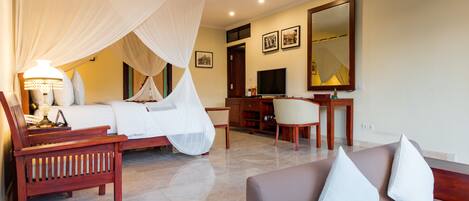 A hotel room with a bed, a desk, a chair, and a sofa.