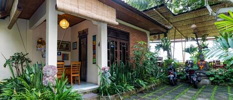 A traditional house with a covered porch, a dining area with chairs, and a motorcycle parked outside.