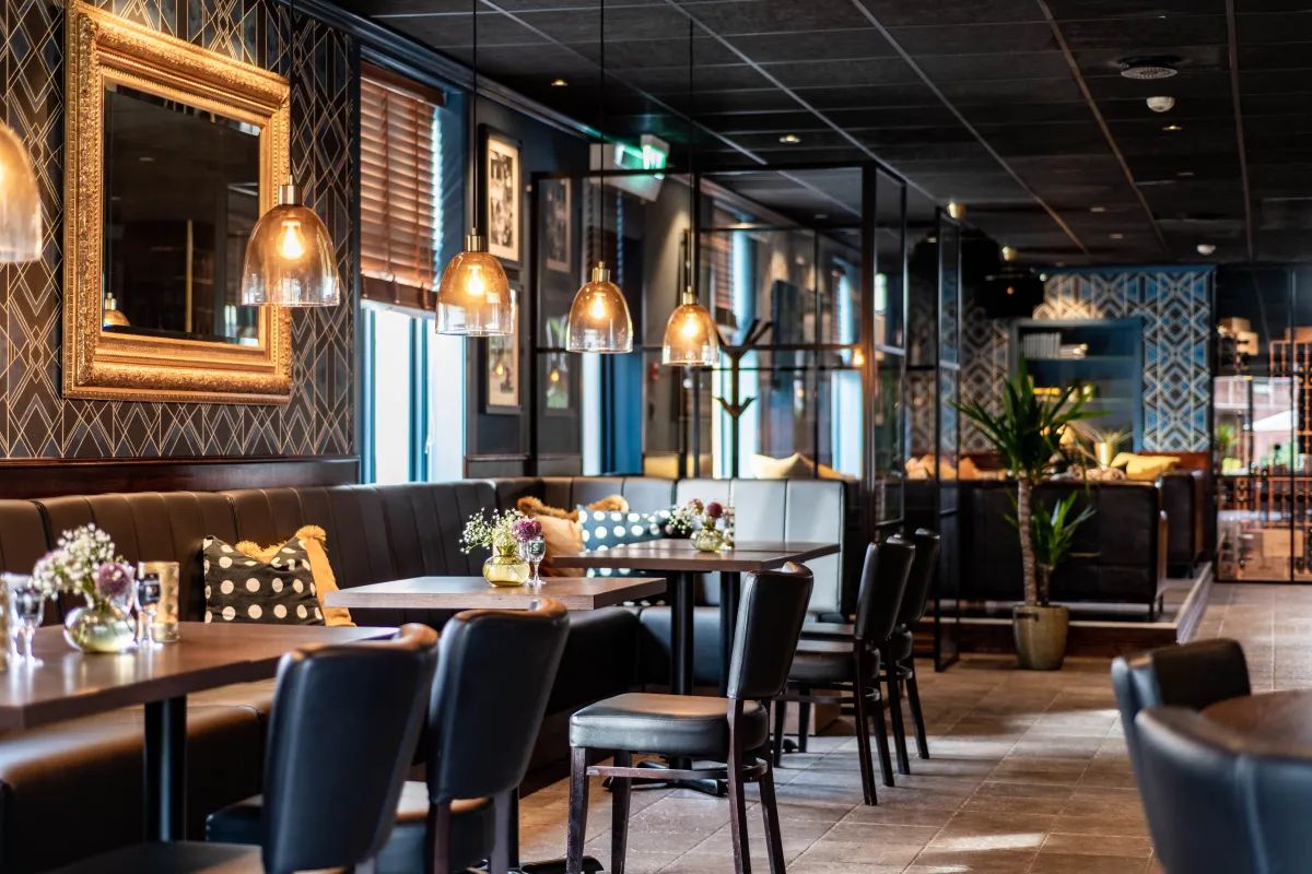 Ein Restaurantinneres mit einer langen Theke, Sitzecken und hängenden Pendelleuchten.