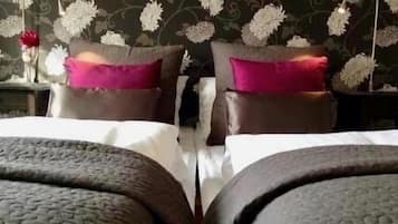 A double bed with a grey headboard and footboard, two pillows, and a nightstand with a vase of flowers.
