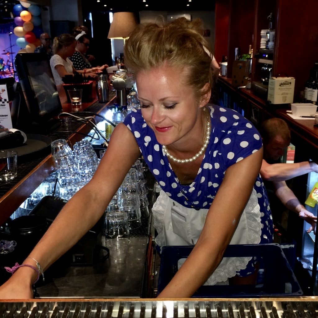 A bar area with a bartender preparing drinks, glasses, and bottles on the counter.
