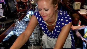 A bar area with a bartender preparing drinks, glasses, and bottles on the counter.