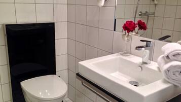 Une salle de bain moderne avec un lavabo blanc, des toilettes et un espace douche.