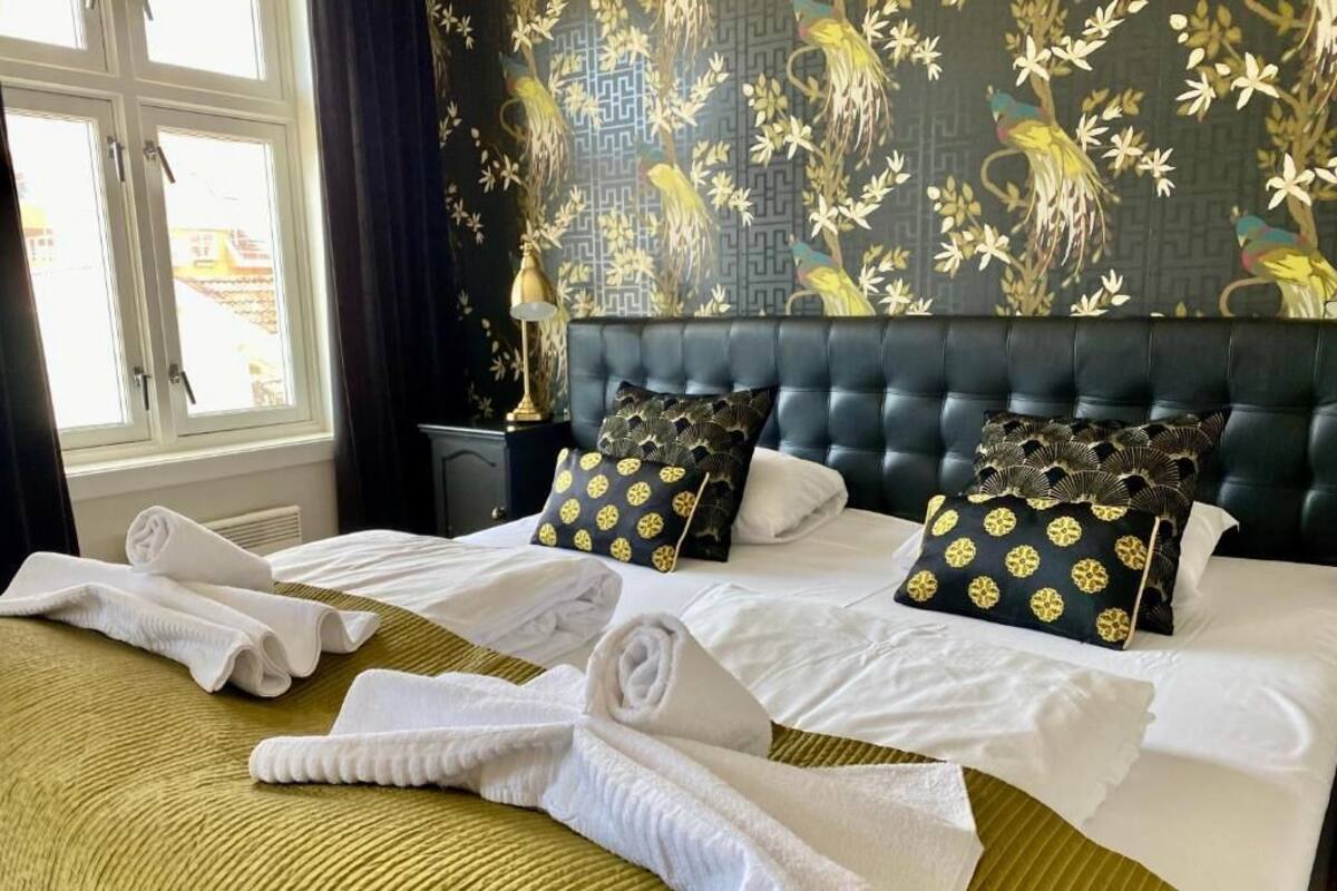 Habitación de hotel con dos camas, un ventanal grande y papel tapiz con motivos florales.