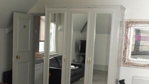 Un dormitorio con un armario grande, una cama, un tocador y una ventana con persianas.