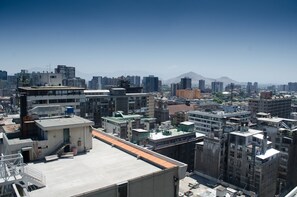 A cityscape with various buildings, including a prominent high-rise with a flat roof and a smaller structure with a staircase. - Boulevard Bellas Artes (Santiago)