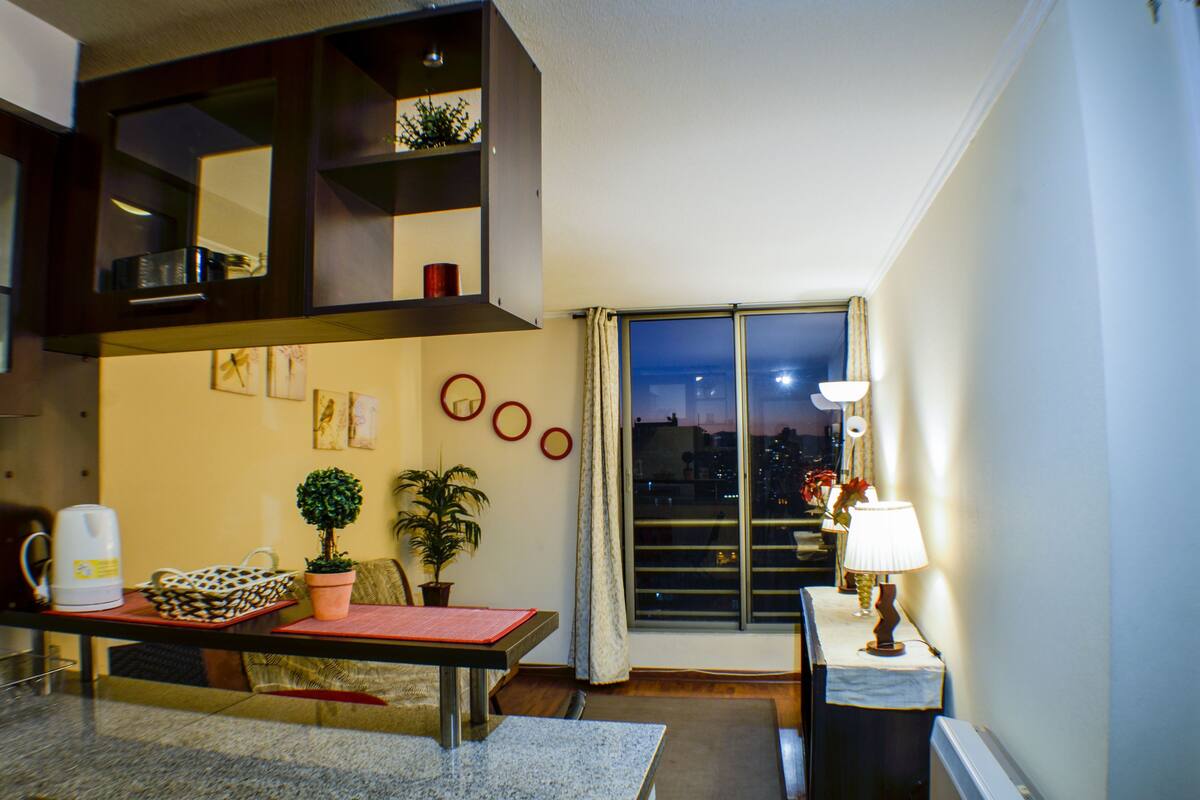 Ein modernes Wohnzimmer mit Essbereich, einem großen Fenster und Blick auf die Stadt sowie einer gemütlichen Atmosphäre.