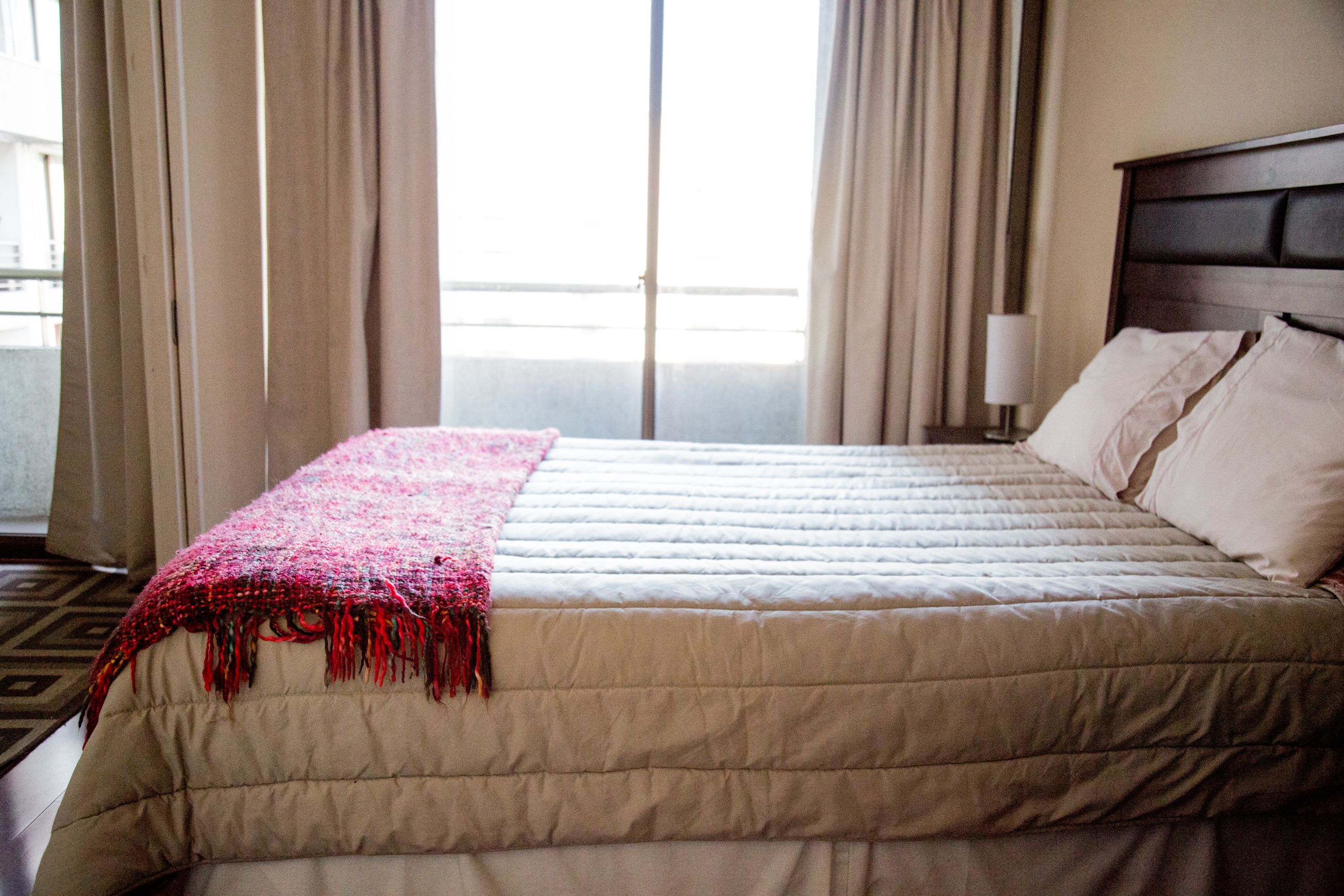 Habitación de hotel con una cama grande, cabecero y una ventana con cortinas.