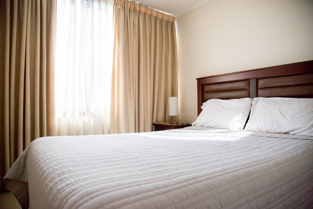 Ein Hotelzimmer mit einem großen Bett, einem hölzernen Kopfteil und einem Nachttisch mit einer Lampe.