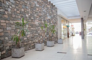 A corridor with a stone wall and potted plants. - Boulevard Bellas Artes (Santiago)